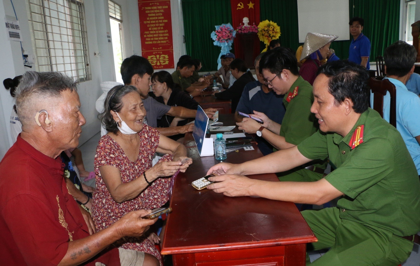 Công an xã Tân Hòa giúp người dân thao tác các ứng dụng trên điện thoại thông minh . (Ảnh: Duy Khương/TTXVN)